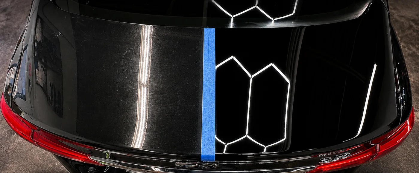 A black hood taped down the middle: swirl-marked paint on the left, corrected paint on the right